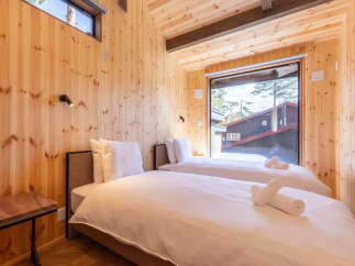 Experience cozy comfort in this charming wooden cabin bedroom, featuring two inviting twin beds dressed in crisp white linens.