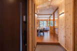 Step into this inviting entryway featuring a rich brown door and a textured doormat, leading to a hallway with warm wood paneling and modern lighting.