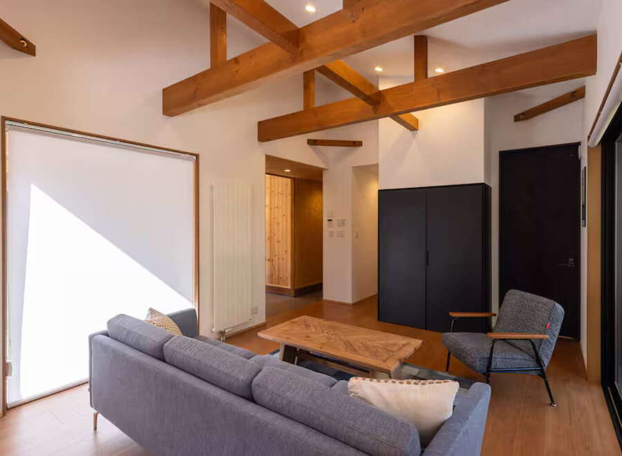 Experience modern living in this spacious open-concept living area, featuring exposed wooden beams and a bright, airy atmosphere.