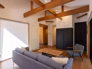 Experience modern living in this spacious open-concept living area, featuring exposed wooden beams and a bright, airy atmosphere.