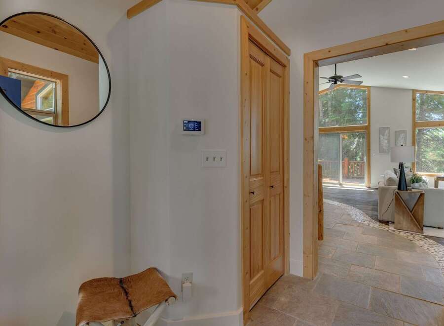 Step into this inviting entryway featuring a stylish round mirror and a unique hide-covered bench, perfect for a warm welcome.