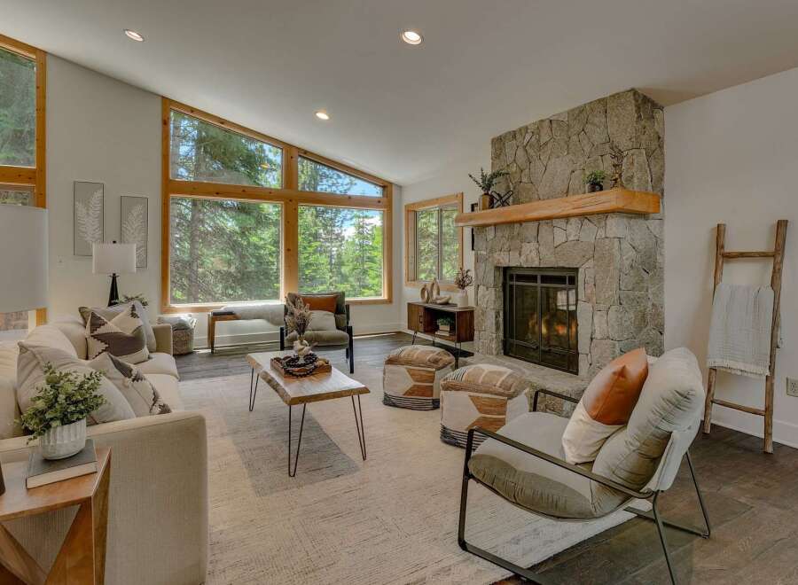 Experience breathtaking forest views from this stunning living room, featuring a grand stone fireplace and expansive windows that flood the space with natural light.