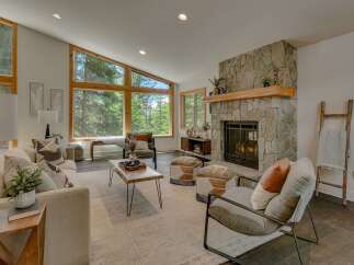 Experience breathtaking forest views from this stunning living room, featuring a grand stone fireplace and expansive windows that flood the space with natural light.
