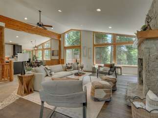 Experience the ultimate mountain retreat in this stunning living room, featuring a grand stone fireplace and expansive windows that bring the outdoors in.
