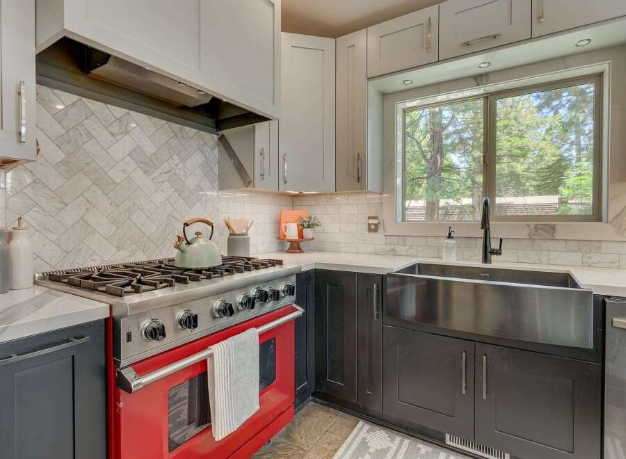Experience culinary excellence in this stunning kitchen, featuring a vibrant red range that adds a pop of color and a professional-grade gas stovetop for precise cooking.