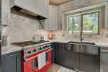 Experience culinary excellence in this stunning kitchen, featuring a vibrant red range that adds a pop of color and a professional-grade gas stovetop for precise cooking.