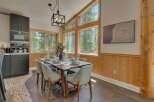 Experience dining amidst nature in this stunning home, featuring a spacious dining area with large windows that offer breathtaking forest views.