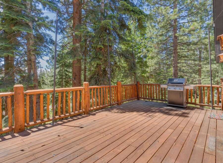 Enjoy outdoor living on this spacious wooden deck, perfect for entertaining or relaxing amidst the serene forest.