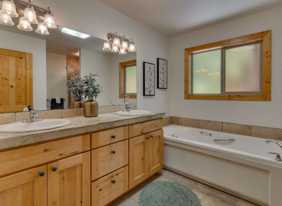 This spacious bathroom features a double vanity with ample counter space and natural wood cabinetry, perfect for storage.
