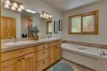 This spacious bathroom features a double vanity with ample counter space and natural wood cabinetry, perfect for storage.