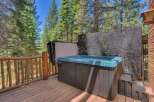 Enjoy ultimate relaxation in this luxurious hot tub, perfectly situated on a spacious wooden deck surrounded by the serene beauty of tall pine trees.