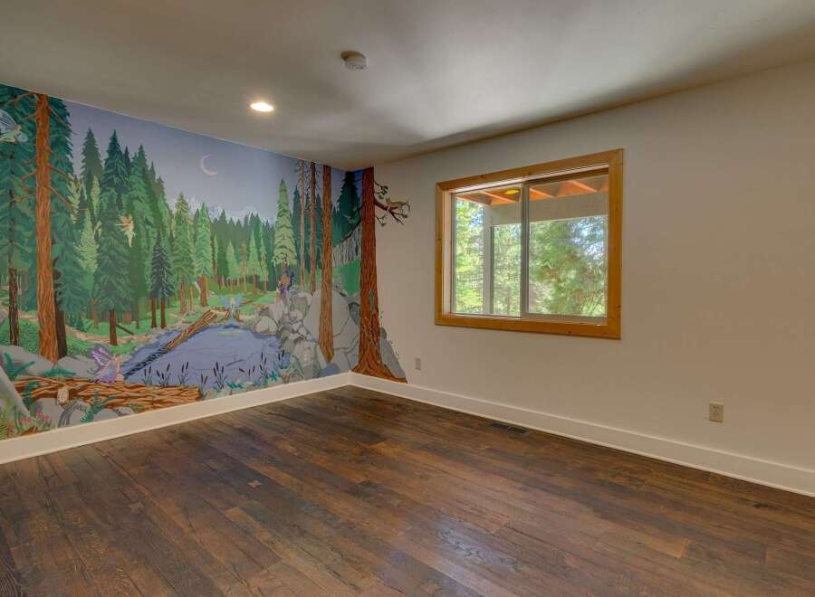 Step into a whimsical forest wonderland with this enchanting mural, featuring playful fairies and a serene stream amidst towering trees.