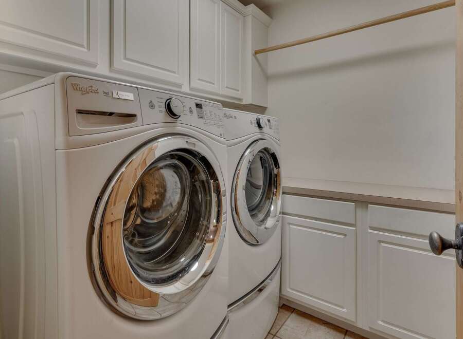 This laundry room features a stacked Whirlpool Duet washer and dryer set, offering ample space for your laundry needs.