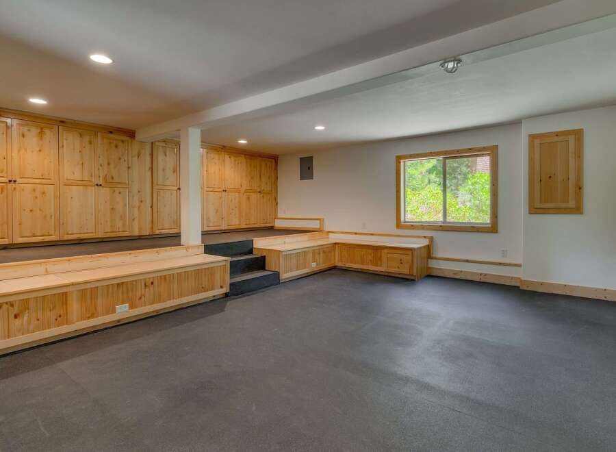 Discover ample storage and versatile seating in this spacious room, featuring custom built-in wooden cabinets and a comfortable L-shaped bench.