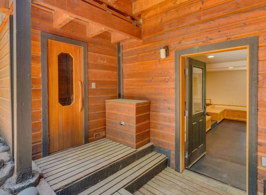 Step onto the charming wooden deck leading to a rustic sauna entrance, perfect for unwinding.