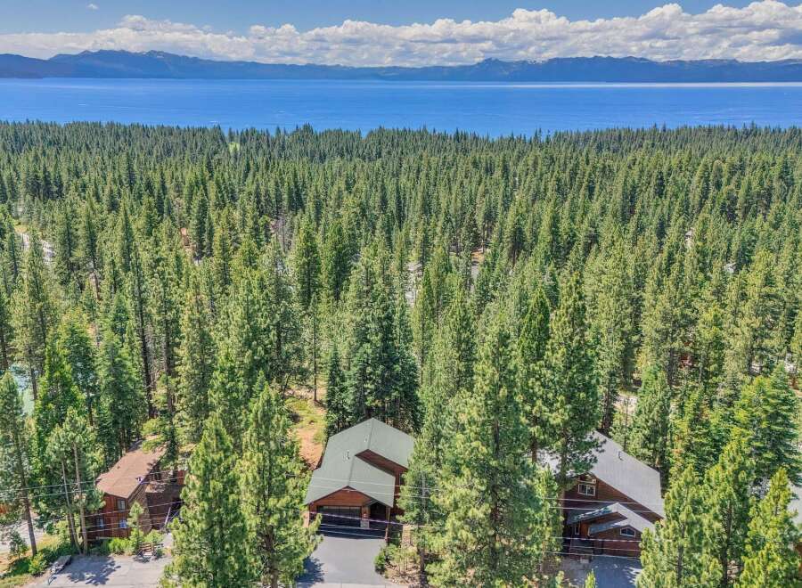 Nestled amidst a dense forest of towering pine trees, this property offers a serene retreat with breathtaking views of a vast blue lake and distant snow-capped mountains.