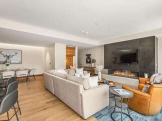 Experience modern luxury in this spacious living area, featuring a sleek fireplace with an integrated TV and comfortable, neutral-toned seating.