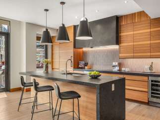 Experience modern luxury in this stunning kitchen, featuring sleek dark countertops and warm wood cabinetry.