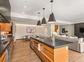 Experience modern luxury in this open-concept living space, featuring a sleek kitchen island with a waterfall countertop and pendant lighting.