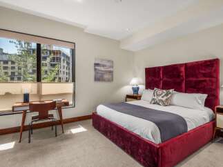 Experience luxury in this stunning bedroom featuring a plush, deep red velvet bed with a commanding headboard.