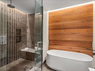 Experience luxury in this modern bathroom featuring a sleek, freestanding bathtub complemented by a warm, wood-paneled accent wall.