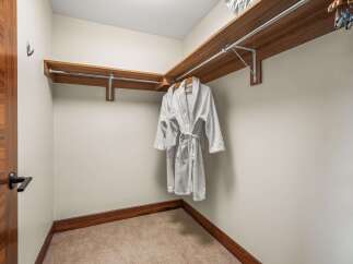Step into this spacious walk-in closet, featuring elegant wood shelving and a convenient hanging rod.