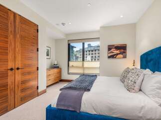 Experience modern comfort in this stylish bedroom, featuring a luxurious blue velvet bed and elegant wood-grain double doors.