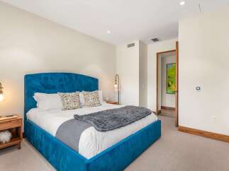 Experience luxury in this beautifully appointed bedroom featuring a striking blue velvet bed as the centerpiece.