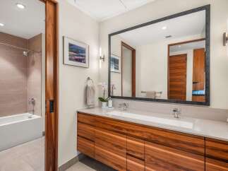 Experience modern luxury in this stunning bathroom, featuring a sleek dual vanity with rich wood cabinetry and a spacious soaking tub.