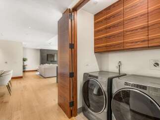 Experience modern living with this beautifully appointed laundry area, featuring sleek, dark wood cabinetry that offers ample storage.