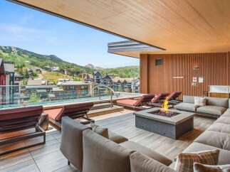 Experience luxury mountain living with this stunning outdoor space, featuring a sleek infinity pool overlooking a picturesque ski village and surrounding peaks.