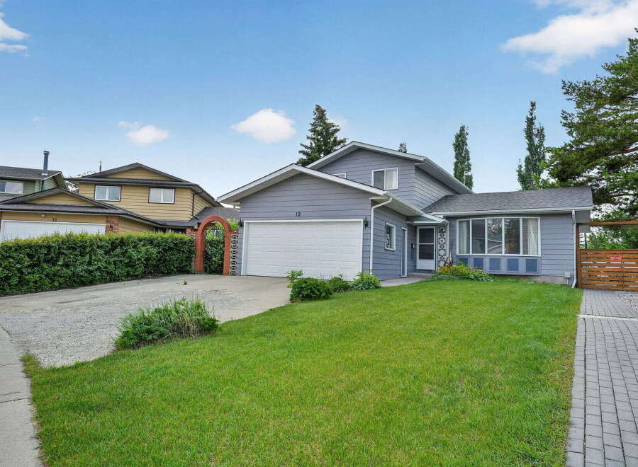 Charming grey siding home with a spacious front lawn and a detached garage.