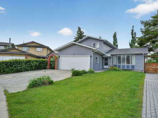 Charming grey siding home with a spacious front lawn and a detached garage.