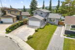 Discover this charming home featuring a well-maintained lawn and a paved driveway leading to an attached garage.