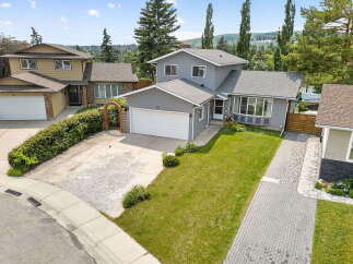 Discover this charming home featuring a well-maintained lawn and a paved driveway leading to an attached garage.