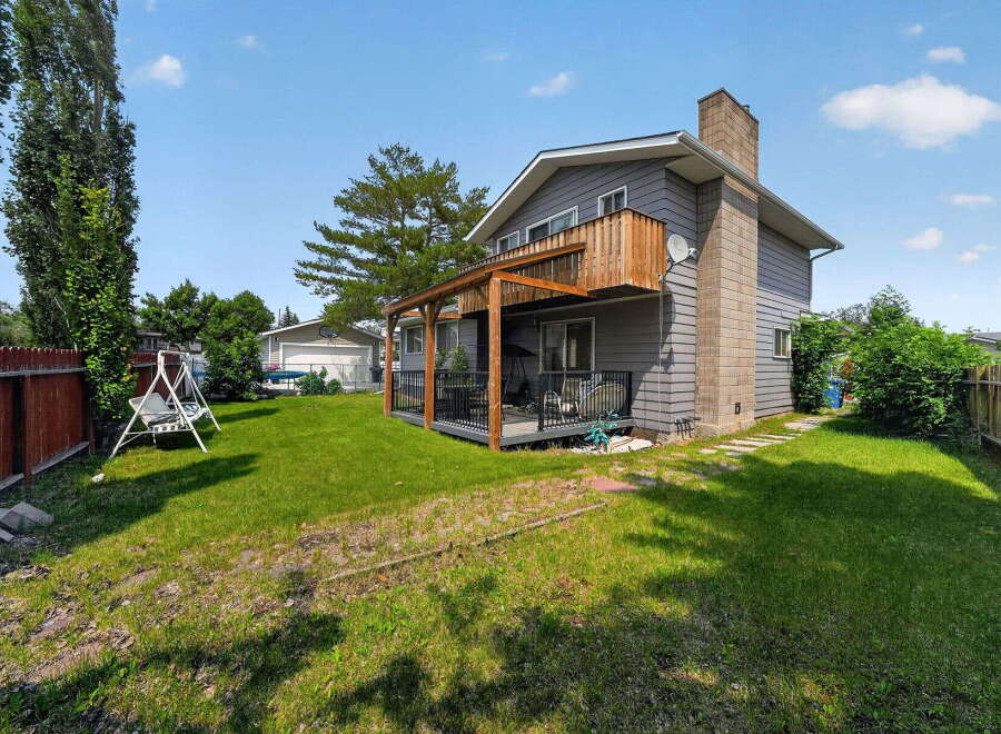 Enjoy outdoor living with this spacious backyard featuring a covered deck and a second-story balcony, perfect for entertaining or relaxing.