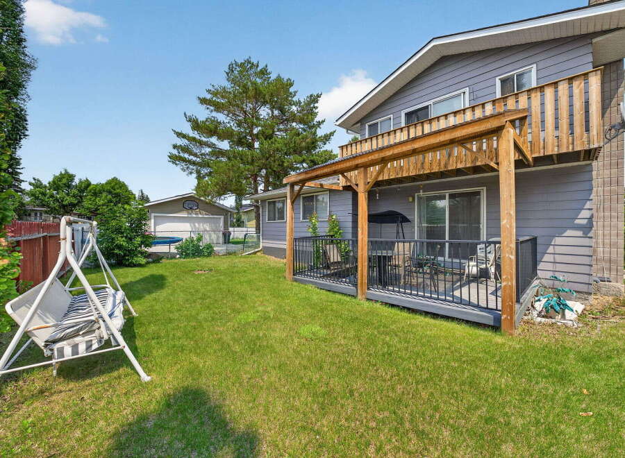 Enjoy outdoor living with this spacious backyard featuring a covered deck perfect for entertaining and a charming swing set for relaxation.