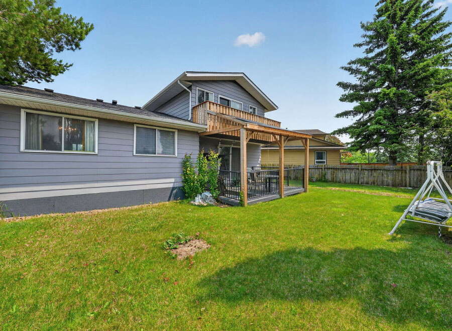 Enjoy outdoor living in this spacious backyard featuring a wooden deck with a pergola, perfect for entertaining or relaxing.