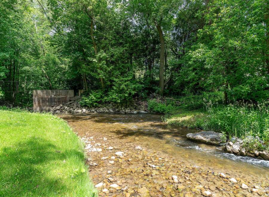 Escape to nature with this serene property featuring a charming creek flowing through lush greenery.