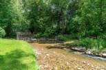 Escape to nature with this serene property featuring a charming creek flowing through lush greenery.