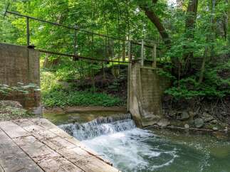 Discover a serene natural escape with this charming property featuring a picturesque waterfall and a rustic wooden bridge.