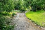 Discover a serene retreat with this charming property, featuring a picturesque stream flowing through lush greenery.