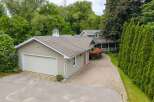 Discover this charming property featuring a spacious garage and a welcoming home nestled amidst lush greenery.