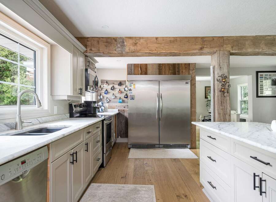 Experience rustic charm in this spacious kitchen, featuring a large stainless steel refrigerator and ample cabinet space.