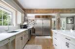 Experience rustic charm in this spacious kitchen, featuring a large stainless steel refrigerator and ample cabinet space.
