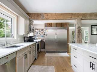 Experience rustic charm in this spacious kitchen, featuring a large stainless steel refrigerator and ample cabinet space.