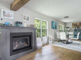 Experience the charm of this inviting living space, featuring a striking gray fireplace as the focal point.