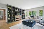 This living room boasts a stunning floor-to-ceiling built-in bookshelf with a modern fireplace and entertainment center.