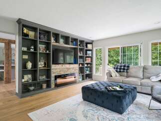 This living room boasts a stunning floor-to-ceiling built-in bookshelf with a modern fireplace and entertainment center.