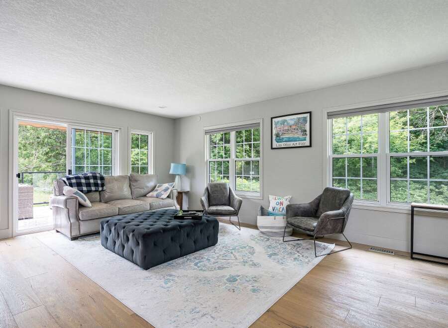 Step into this inviting living room, bathed in natural light from large windows overlooking lush greenery.